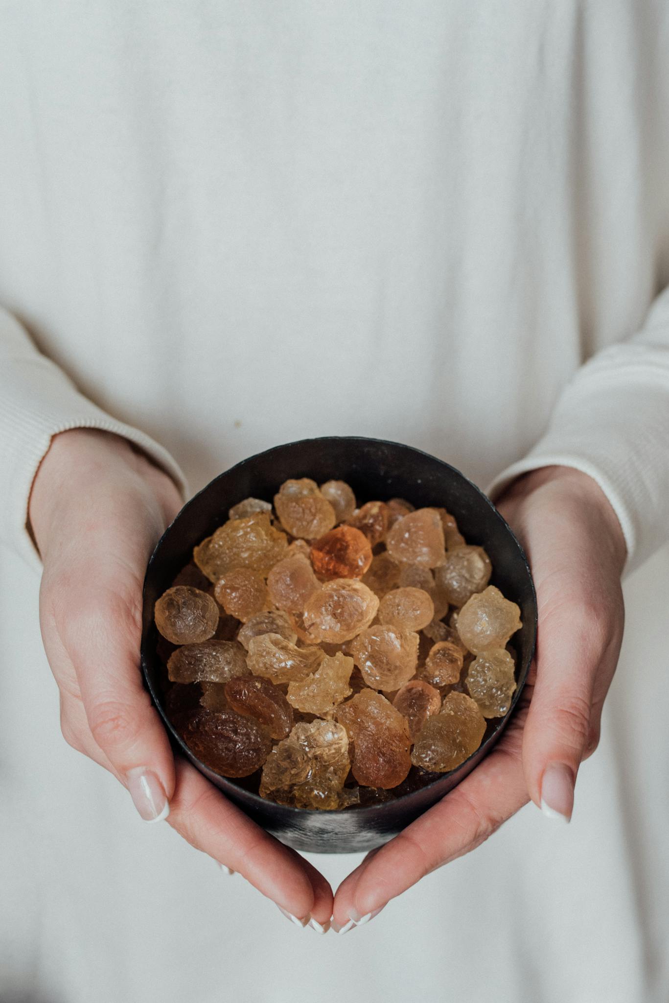 Hands gently holding a bowl filled with healing crystals for holistic therapy.